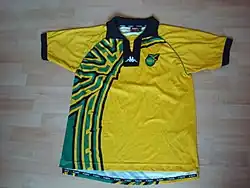 photo d'un maillot jaune avec une bande verte sur le côté droit posé sur un parquet
