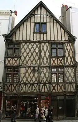  Photographie d'une façade d'une maison jumelle à colombages et pignon.
