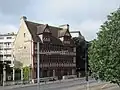 La façade à pan de bois, sur mur gouttereau en pierre de Caen.
