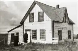 Deux hommes en soutane situés devant une maison.