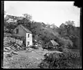 Paysage : maison et lavoir au pied d'une colline.