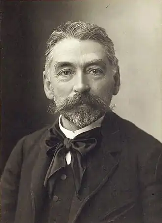 Photographie noir et blanc d'un homme barbu, de face.