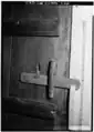 Loquet en bois sur une porte de chambre à Norwichtown  (États-Unis). Une tirette en corde permet de relever le battant depuis l'extérieur.