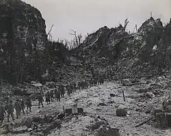 Photo en noir et blanc de soldats au milieu d'un paysage dévasté.