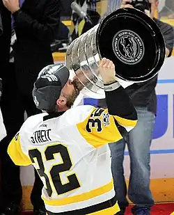 Photographie d'un joueur de hockey de dos brandissant la Coupe Stanley
