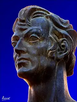 Photo couleur d'un buste en bronze. Trois-quart avant droit. Cheveux en arrière.