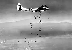 Photo noir un blanc d'un avion en train de larguer des grappes de bombes