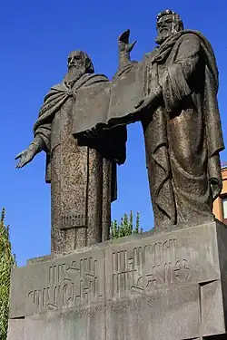 Statues de deux hommes côte à côte, présentant un livre.