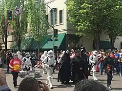 Photographie en couleurs d'un défilé de personnages costumés dans une rue.