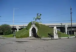 Vue d'un bâtiment circulaire, couvert d'herbe et surmonté d'une statue équestre.