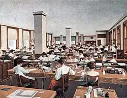 Dessin d'un grande salle aux murs blancs avec des bureaux en bois où travaillent des dizaines de femmes.
