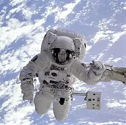 L'astronaute Michel Gernhardt au bout du bras robotisé de la navette Endeavour. Photo prise lors d'une sortie extra-véhiculaire dans le cadre de la mission STS-69 en 1995. En arrière-plan, la Terre.
