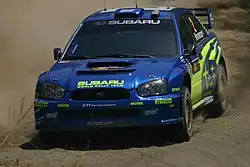 Voiture bleu foncé, vue de face, sur de la terre.