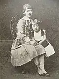 Deux petites filles en habits anciens posent assises pour une photos.