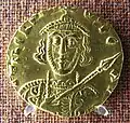 Zoom sur la face d'un solidus représentant Tibère, au visage élancé et tenant la lance.