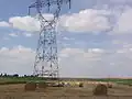 Paysage avec pylônes électriques et éoliennes.