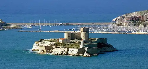 Le château d'If et son phare devant le port des îles Ratonneau et Pomègues. En fond du port, la digue de Berry faisant la jonction entre les deux îles.