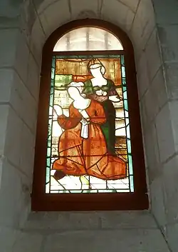 Vue, depuis l'intérieur, d'un petit vitrail représentant deux personnages.