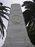 Face d'un obélisque de marbre blanc avec un médaillon représentant un profil dans une couronne de laurier