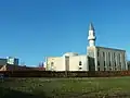 photo d'une mosquée surmontée d'un minaret sur fond de ciel bleu.