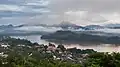 Montagnes avec de la brume et des nuages bas, eau boueuse du Mékong, et habitations parmi les arbres, durant la mousson, vus du Mont Phou Si, au lever du soleil (6h du matin) à Luang Prabang.Septembre 2023.