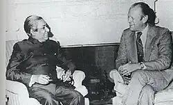Deux hommes assis dans des fauteuils se regardent.