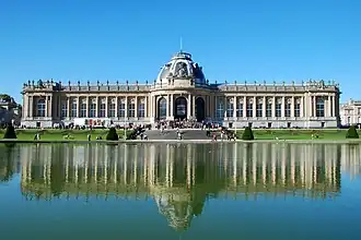  photographie actuelle de la façade arrière du bâtiment imposant en pierre claire à l'arrière d'un plan d'eau et de jardins