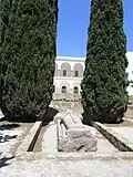 Vue d'une statue allongée avec une épée et un édifice à colonnade à l'arrière-plan.