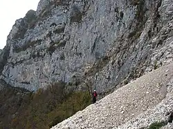 Randonneur franchissant des éboulis au pied d'une montagne.