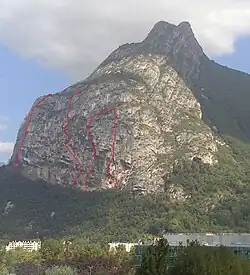 Tracé de 4 voies d'escalade dans une paroi verticale terminant une crête rocheuse vue en contre-plongée.