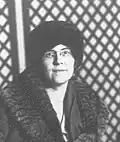 Photo nr/bl d’une femme en manteau col et toque de fourrure vue de face, portant des lunettes de formes ovales
