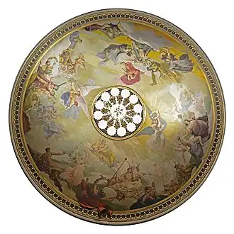 Vue du dessous, une peinture circulaire, avec des personnage de style antique. Au centre, le lustre allumé.