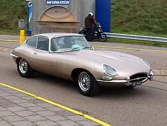Photographie trois quart avant d'une Jaguar Type E roadster rouge stationnée sur un emplacement de parking