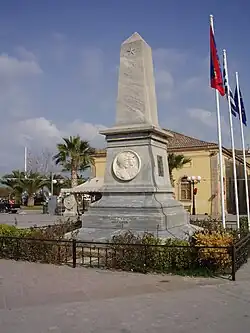 photographie couleurs : un monument de type obélisque en pierre grise et des drapeaux
