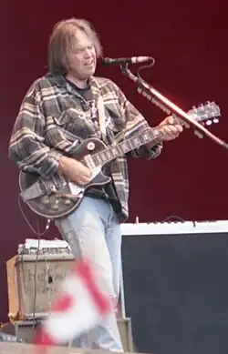 A gray-haired man playing a guitar