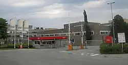 Un bâtiment industriel gris à trois étages, avec trois drapeaux "Nidar" à l'entrée.