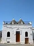 Trullo à la façade rehaussée cachant les deux cônes de toiture (Alberobello)