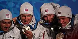 Photo de quatre hommes de face, chacun montrant leur médaille