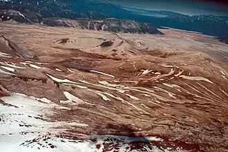 Vue générale du Novarupta composé de sa caldeira peu marquée et de son dôme de lave ; la vallée des Dix Mille Fumées est visible en haut à droite.