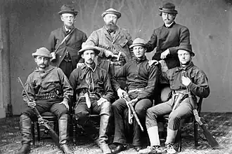 Photo en noir et blanc d'un groupe de paléontologues armées de fusils