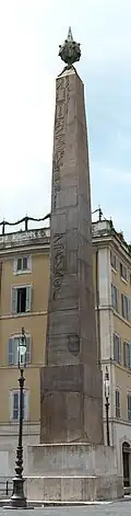 Grande obélisque en pierre sculptée surmontée d'une boule métallique.