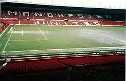 Tribune d'un stade de football avec des sièges rouges sur laquelle est inscrit : « Manchester United »