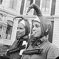 Deux jeunes filles bizutées, coiffées d'un bonnet à grelot, à La Haye (5 septembre 1961). L'une a une tétine à la bouche.