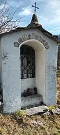 Photographie d'un oratoire avec ses murs bleutés et sa grille.