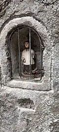 Photographie d'un oratoire vu de face, avec la une statuette dedans.