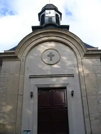 Photo d'un bâtiment surmonté d'un clocher, avec une grande porte rouge