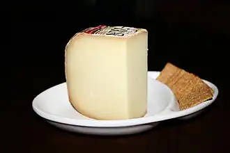 Vue d’une assiette blanche contenant une tranche de tomme de fromage et des biscuits rectangulaires.