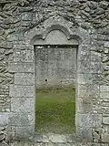 Cette porte du XIIIe&nbsp;siècle est rectangulaire et surmontée d'un arc en mitre trilobé incrusté de trois trèfles à quatre feuilles.
