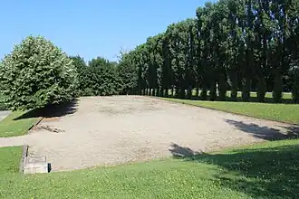 Terrain sablonneux entouré d'arbres.