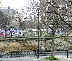 La rue longe l'ancienne ligne de Petite Ceinture décorée de nos jours par de nombreux graffitis.